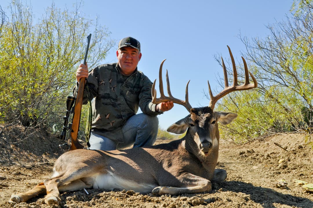 Hunter holding impressive whitetail antlers from his ranch harvest